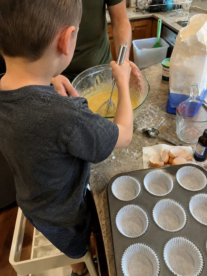 Child helping cook with push whisk