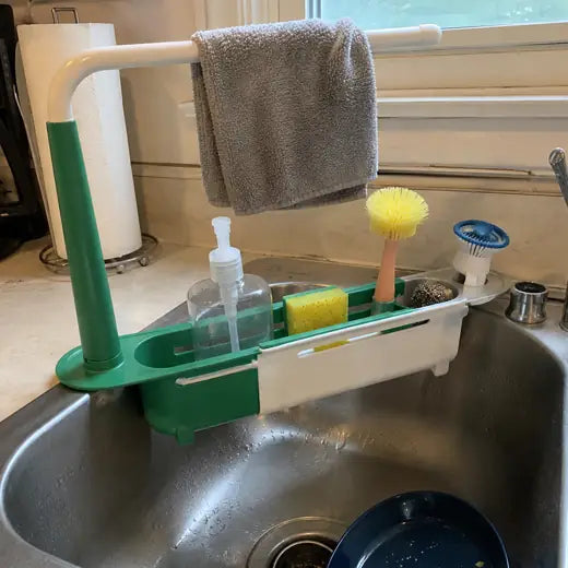 Green telescopic sink rack holding soap sponge brush and towel