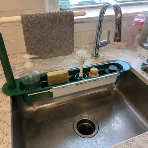 Green expandable sink organizer installed across a kitchen sink