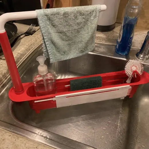 Red sink rack storing dish soap sponge towel and brush