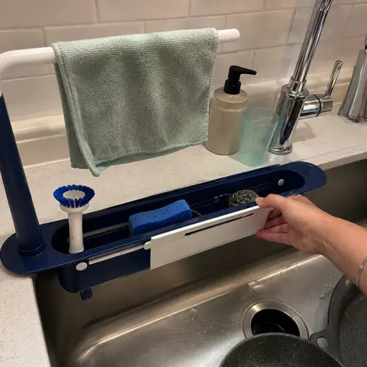 Blue telescopic sink organizer being adjusted beside faucet