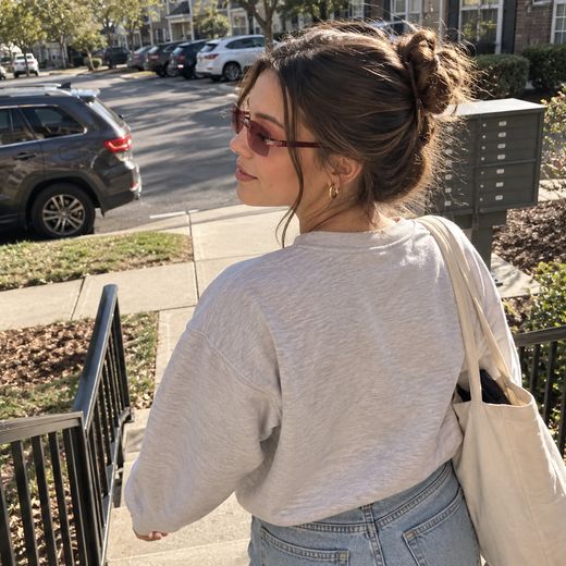 Woman outdoors wearing rose smart zoom glasses on sunny steps